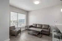 Bright and modern living area with sleek brown seating, large window with city view, and stylish furniture in an open-concept apartment.