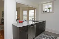 Elegant modern kitchen with sleek granite countertops, open view to a sunlit dining area, and contemporary stainless steel appliances.