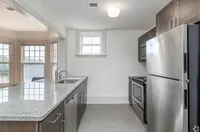 Bright, modern kitchen with stainless steel appliances, chic dark cabinets, and expansive windows flooding the space with natural light.