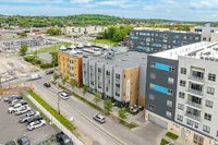 Charming urban apartment complex with modern design, nestled in a vibrant neighborhood with lush green surroundings and ample parking.