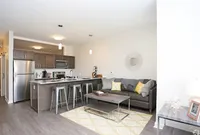 Contemporary open-plan living area with a sleek kitchen featuring stainless steel appliances, a cozy sofa with decorative pillows, and stylish modern decor.