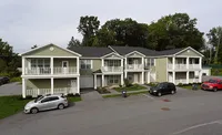 Charming townhouse complex with elegant balconies, nestled in lush greenery, offering cozy and modern living spaces.