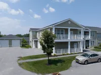 Charming two-story apartment building with inviting balconies, individual garages, and lush greenery, ideal for modern living.