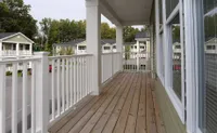 Charming apartment balcony with white railings and a view of lush greenery and neighboring homes, perfect for relaxing.