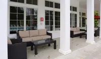 Patio area by the Kensington private pool with overhead coverage, couches, and tables.