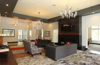 Elegant clubhouse room with modern chandeliers, cozy seating arrangement, and a sleek fireplace, perfect for relaxation and entertaining.