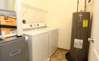 Bright laundry room featuring modern washer and dryer, efficient utility setup with water heater.
