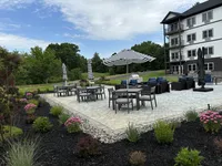 Charming outdoor patio with stylish furniture and vibrant garden, perfect for relaxing and entertaining by a modern apartment building.