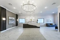 Elegant apartment lobby featuring a modern chandelier, marble floor tiles, and a stylish reception desk.