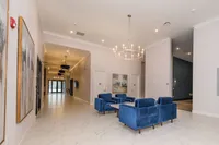 Luxurious apartment lobby with elegant chandelier, modern artwork, and plush blue seating area.