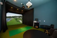 Modern entertainment room featuring a state-of-the-art golf simulator, surrounded by elegant seating and ambient lighting.