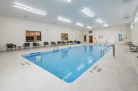 Elegant indoor pool area with modern seating, bright lighting, and sleek tile flooring, perfect for relaxation and leisure.