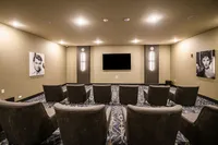 Elegant private cinema room with plush seating, modern lighting, and a large flat-screen TV, perfect for a luxurious movie experience.