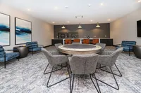 Luxurious entertainment room with a chic circular gaming table, plush seating, and modern art accents.