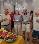Vibrant community gathering in a stylish apartment setting, showcasing a well-lit room with modern decor and a table filled with a variety of snacks and drinks.