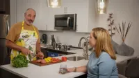 Contemporary kitchen featuring a stylish couple preparing fresh vegetables, showcasing a modern countertop and sleek appliances.