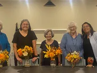 Joyful group standing behind a table adorned with vibrant autumn-themed floral arrangements, creating a warm and inviting atmosphere.