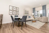 Bright and modern living room with elegant decor, featuring stylish furniture, cozy dining area, and large windows with sheer curtains for plenty of natural light.