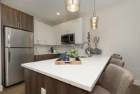 Modern kitchen with elegant white and wood cabinetry, sleek stainless steel appliances, and chic pendant lighting.