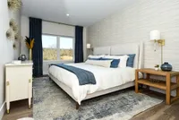 Modern bedroom with elegant design features a cozy bed, chic decor, large window view, and warm lighting.