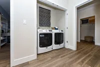 Modern laundry area in a stylish apartment featuring high-efficiency washer and dryer with elegant wood flooring.