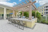 Charming outdoor patio with a stylish pergola, featuring a sleek granite bar area surrounded by lush tropical greenery.