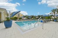 Inviting outdoor pool area with stylish lounge chairs and vibrant blue umbrellas set against a clear sky, perfect for relaxation and leisure.