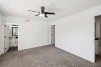 Bright, spacious bedroom with modern ceiling fan and plush carpeting, featuring a stylish en-suite bathroom.