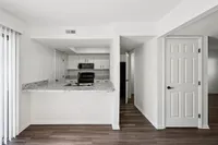 Modern kitchen with sleek granite countertops, white cabinetry, and open layout in a stylish apartment.