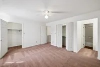 Bright and spacious bedroom with plush carpet, generous closet space, and modern ceiling fan.