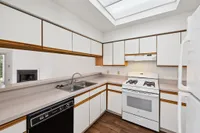 Bright and inviting kitchen with sleek white cabinets, modern appliances, and ample counter space, featuring a cozy view into the adjacent living area with a fireplace.