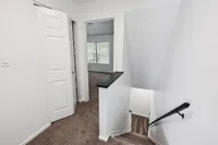 Inviting staircase leading to a bright room with large windows and plush carpeting, perfect for a cozy living space.