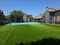 Pickleball Court Inviting outdoor tennis court surrounded by lush green landscaping and modern apartment buildings.