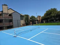 Pickleball Court Inviting apartment complex with modern tennis court and lush greenery, perfect for sports enthusiasts and outdoor lovers.