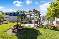 Charming outdoor area with a shaded pergola and picnic table, perfect for relaxation near a sparkling swimming pool.