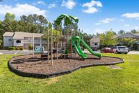 Inviting community playground with vibrant green slides surrounded by lush greenery, ideal for family-friendly living.