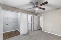 Modern apartment interior showcasing a spacious room with soft carpeting, a ceiling fan, and a versatile closet space, perfect for comfortable living.