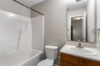 Modern bathroom with sleek fixtures, featuring a full-size bathtub, elegant vanity, and large mirror, perfect for a refreshing retreat.