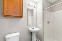 Elegant bathroom featuring a modern pedestal sink, stylish mirror, and sleek shower area with warm lighting.