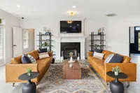 Modern living room featuring elegant leather sofas, chic black tables, and a cozy fireplace, styled with earthy decor and a vibrant area rug.