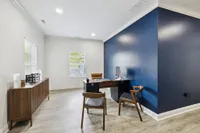 Sophisticated office space with contemporary wooden furniture, accented by a bold blue wall and natural light.