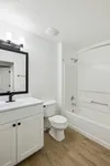 Modern bathroom with sleek white vanity, stylish mirror, and elegant wood flooring.