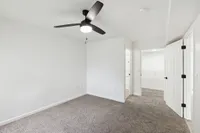 Bright and inviting bedroom featuring plush carpet and a modern ceiling fan, leading to a spacious, well-organized walk-in closet.