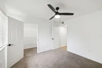 Bright and airy bedroom with plush carpet, modern ceiling fan, and expansive walk-in closet.