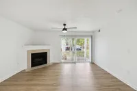 Bright and airy living room with elegant hardwood flooring, a cozy fireplace, and large sliding glass doors leading to a serene outdoor view.
