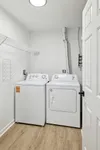 Modern laundry room with efficient washer and dryer, featuring sleek white appliances and elegant wood flooring.
