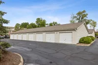 Spacious apartment complex with multiple secure garages, surrounded by lush greenery and a serene ambiance.