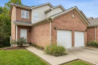 Charming suburban home with a red brick exterior, double garage, and well-maintained front yard landscape.