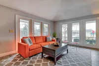 Bright and stylish living room featuring a vibrant orange sofa, elegant coffee table, and large windows for natural light.