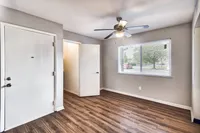 Inviting entryway with sleek wooden flooring and abundant natural light through a large window, complemented by a ceiling fan for comfort.